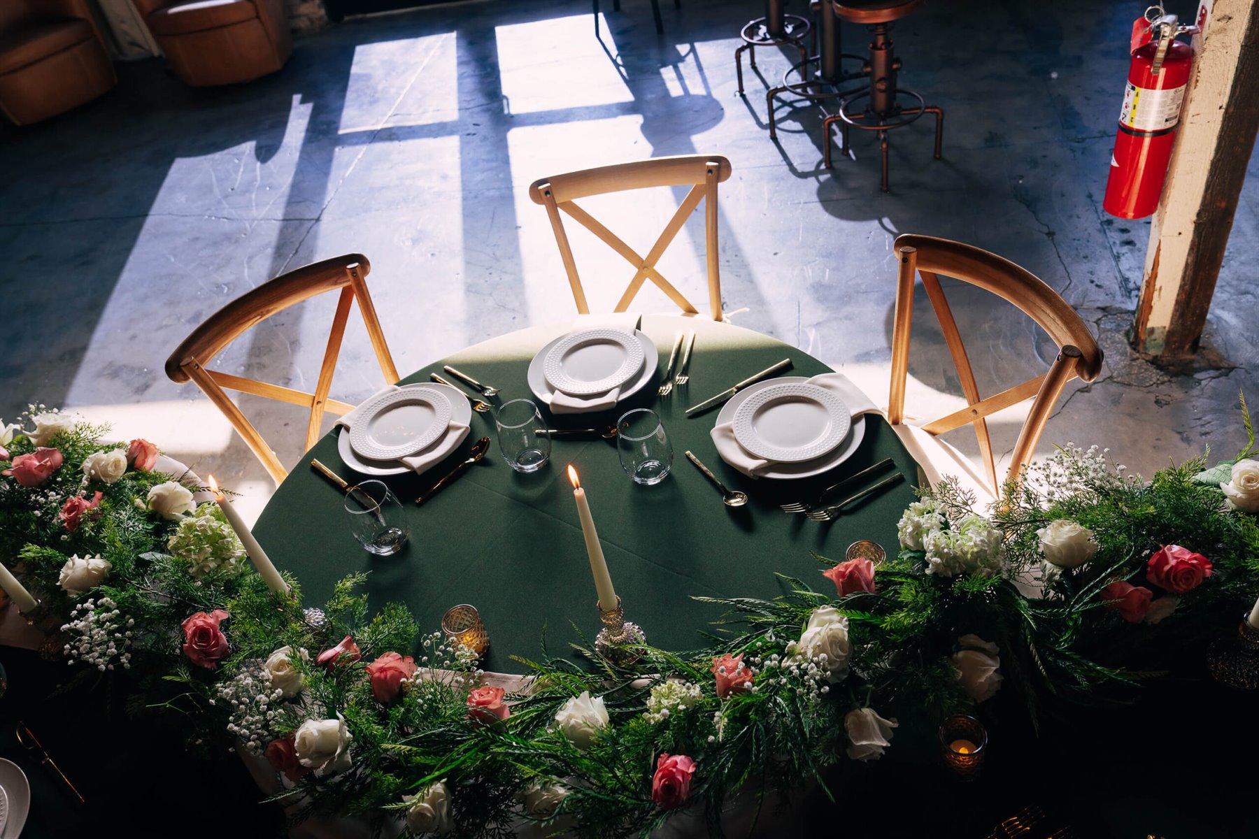 A round table laid with greenery, candles and gold cutlery on the event floor at The Cove