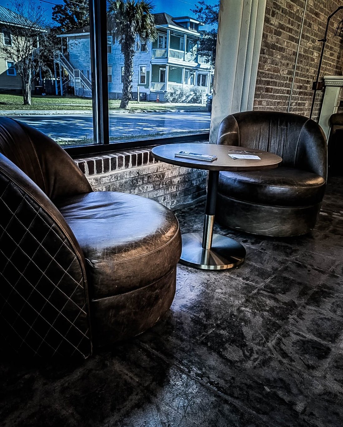 Leather club chairs and a café table by the window at The Cove, looking out onto Springfield