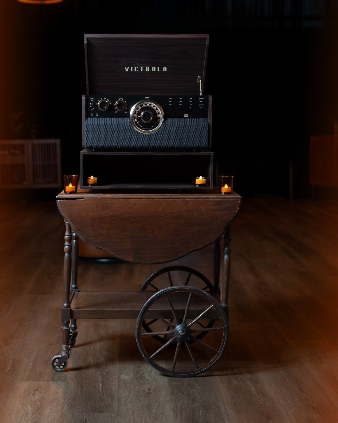A record player on a vintage tea cart, lit by candles, on the floor at The Cove